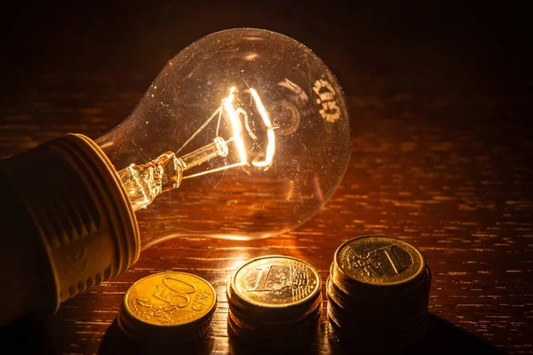 Münzen Auf Dunkler Oberfläche Daneben Eine Glühbirne Energiewert Und Energieeinsparung — Stockfoto
