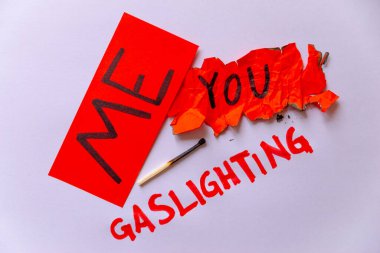 Patolojik narsisizm, narsisizm ve Gaslighting. Üzerinde benim yazılı kırmızı kağıt, buruşuk ve yırtık kırmızı kağıt üzerine sen yazmışsın, Gaslighting yanında beyaz arka planda kırmızı ile yazılmış..