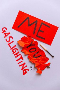 Patolojik narsisizm, narsisizm ve Gaslighting. Üzerinde benim yazılı kırmızı kağıt, buruşuk ve yırtık kırmızı kağıt üzerine sen yazmışsın, Gaslighting yanında beyaz arka planda kırmızı ile yazılmış..