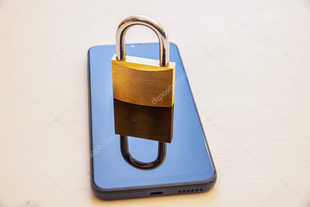 Smartphone placed on a white surface, with a padlock on it. Security and inviolability of electronic devices and protection of their data.