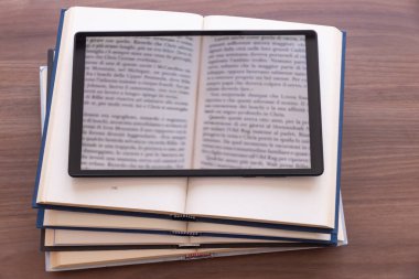 Üstünde tablet olan açık kitapları üst üste koyuyor. E-kitap ve e-okuyucu. Dijital biçimdeki kitaplar.
