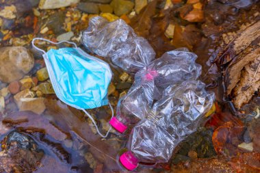 Nehrin sularına atılan maske ve plastik şişeler..