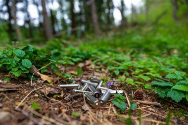 Çimenlere atılmış tükenmiş piller, bir ağaçta. Ekoloji ve çevre koruma. Kirletici atıkların bertaraf edilmesi.