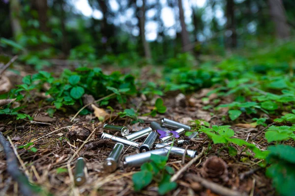 Çimenlere atılmış tükenmiş piller, bir ağaçta. Ekoloji ve çevre koruma. Kirletici atıkların bertaraf edilmesi.