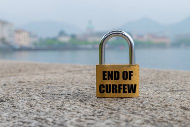 Open padlock with black writing end of curfew in english language.  clipart