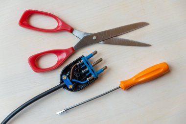 Açık elektrik prizi, tornavida ve makas tahta yüzeyde. Elektrik kablolarına bir kablo bağlıyorum. Kendin tamir et.. 