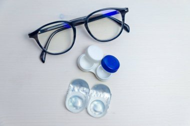 Kontakt lensler, kontak lens ambalajı ve beyaz yüzeydeki lens kabı. Görüş düzeltmesi ve gözlük ve kontakt lensler arasındaki alternatif. 