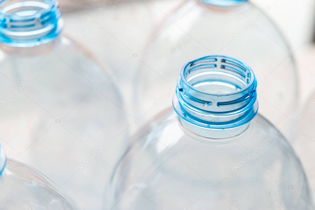 Transparent plastic bottles, on a clear surface. Transparent bottle neck. Recycling and disposal of single-use plastics. 