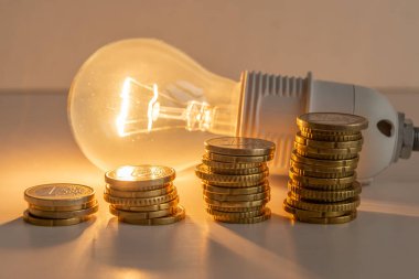 Yanında bozuk paralar olan bir ampul. Enerji tarifelerini arttırın. Verimlilik ve enerji tasarrufu. 