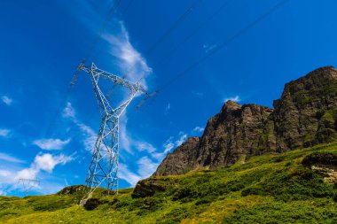 Elektrik direkleri, bir dağ yerinde. Köken, ulaşım ve elektrik ihtiyacı. Çevresel tahribat. Elektirik ızgarası.