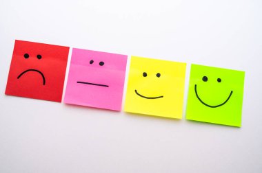 The concept of satisfaction or happiness, expressed with colorful sticky notes, with faces drawn on them, from sad to happy.