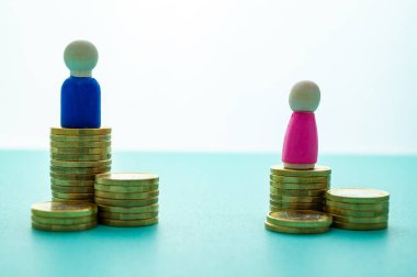Kadınlar ve erkekler arasındaki iş yerinde eşit ücret kavramı. Cinsiyet Ödeme Boşluğu: Ahşap rakamlar ve bozuk para yığınları.