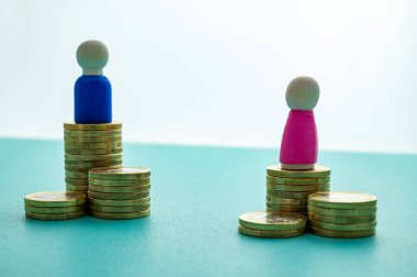 Kadınlar ve erkekler arasındaki iş yerinde eşit ücret kavramı. Cinsiyet Ödeme Boşluğu: Ahşap rakamlar ve bozuk para yığınları.