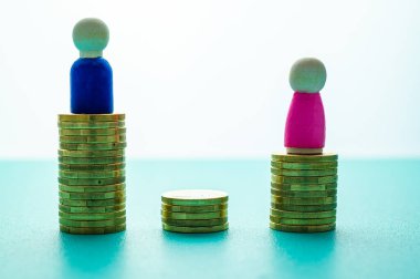 Kadınlar ve erkekler arasındaki iş yerinde eşit ücret kavramı. Cinsiyet Ödeme Boşluğu: Ahşap rakamlar ve bozuk para yığınları.