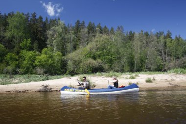 insanlar Gauja Nehri üzerinde bir kano gezisi