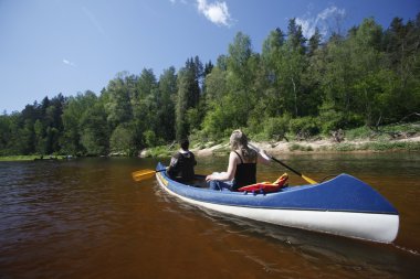 insanlar Gauja Nehri üzerinde bir kano gezisi