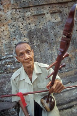 Kamboçya 'nın batısındaki Siem Reap şehrinin yakınlarındaki Angkor Tapınağı' ndaki Pre Rup Tapınağı 'nda bir adam Khmer müziği çalar. Kamboçya, Siem Reap, Şubat 2001