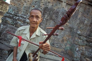 Kamboçya 'nın batısındaki Siem Reap şehrinin yakınlarındaki Angkor Tapınağı' ndaki Pre Rup Tapınağı 'nda bir adam Khmer müziği çalar. Kamboçya, Siem Reap, Şubat 2001