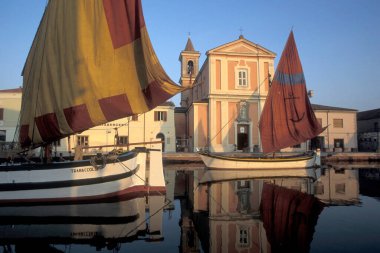 İtalya 'nın Emilia-Romagna kentindeki Cesenatico kasabasındaki Saint James kilisesinin bulunduğu kanal portosunda geleneksel balıkçı tekneleri. İtalya, Cesenatico, Haziran 2001
