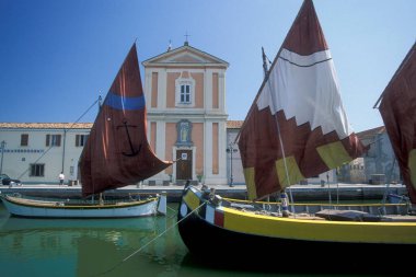 İtalya 'nın Emilia-Romagna kentindeki Cesenatico kasabasındaki Saint James kilisesinin bulunduğu kanal portosunda geleneksel balıkçı tekneleri. İtalya, Cesenatico, Haziran 2001