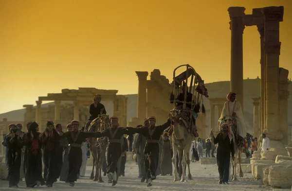 Gente en camellos cerca de ruinas romanas — Foto de Stock