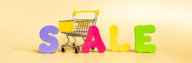 Kelime satışı parlak renkli mektuplarla ve pastel arka planda izole edilmiş alışveriş arabasıyla yazıldı. Pankart.