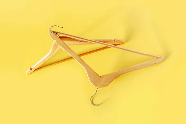 Empty wooden clothes hangers on pastel pink and yellow background . Sale and shopping concept.