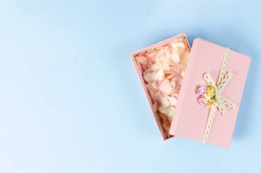 Mavi arka planda pembe konfetilerin yumuşak pembe kalpleriyle dolu pembe hediye kutusu. Sevgililer Günü, düğün, aşk konsepti. Üst görünüm, düz görünüm, kopyalama alanı.