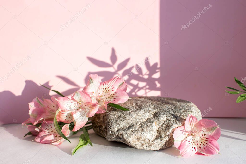 Natural stone stand with flowers for presentation and exhibitions on pink background. Abstract trendy podium for organic cosmetic products. Minimal style.