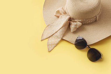 Sarı arka planda hasır şapka ve güneş gözlüğü. Yaz tatili, tatil, seyahat konsepti. Düz konum, üst görünüm, kopyalama alanı. Asgari biçim