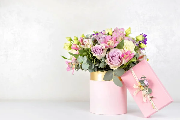 Beautiful bouquet of flowers in round box and pink gift box on a white table. Gift for holiday, birthday, Wedding, Mother\'s Day, Valentine\'s day, Women\'s Day. Floral arrangement in a hat box.