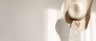 Kadınlar hasır şapkalarını arka plandaki gölgeli beyaz duvara asarlar. Yaz plajı moda konsepti. Kopyalama alanı olan pankart