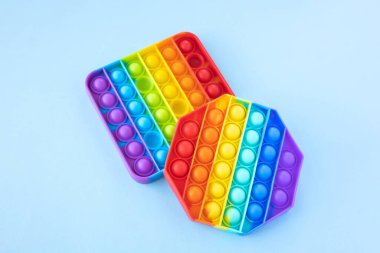 Renkli stres önleyici hareketler mavi arka planda izole edilmiş duyusal oyuncaklar. Basit bir gamze. Üst manzara, düz yatış. Seçici odak.