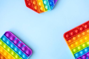 Renkli stres önleyici hareketler mavi arka planda izole edilmiş ve fotokopi alanı olan çocuklar için duyusal oyuncaklar. Basit bir gamze. Üst manzara, düz yatış. Seçici odak.