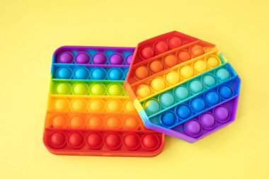 Renkli stres önleyici hareketler sarı arka planda izole edilmiş çocuklar için duyusal oyuncaklar. Basit bir gamze. Üst manzara, düz yatış. Seçici odak.