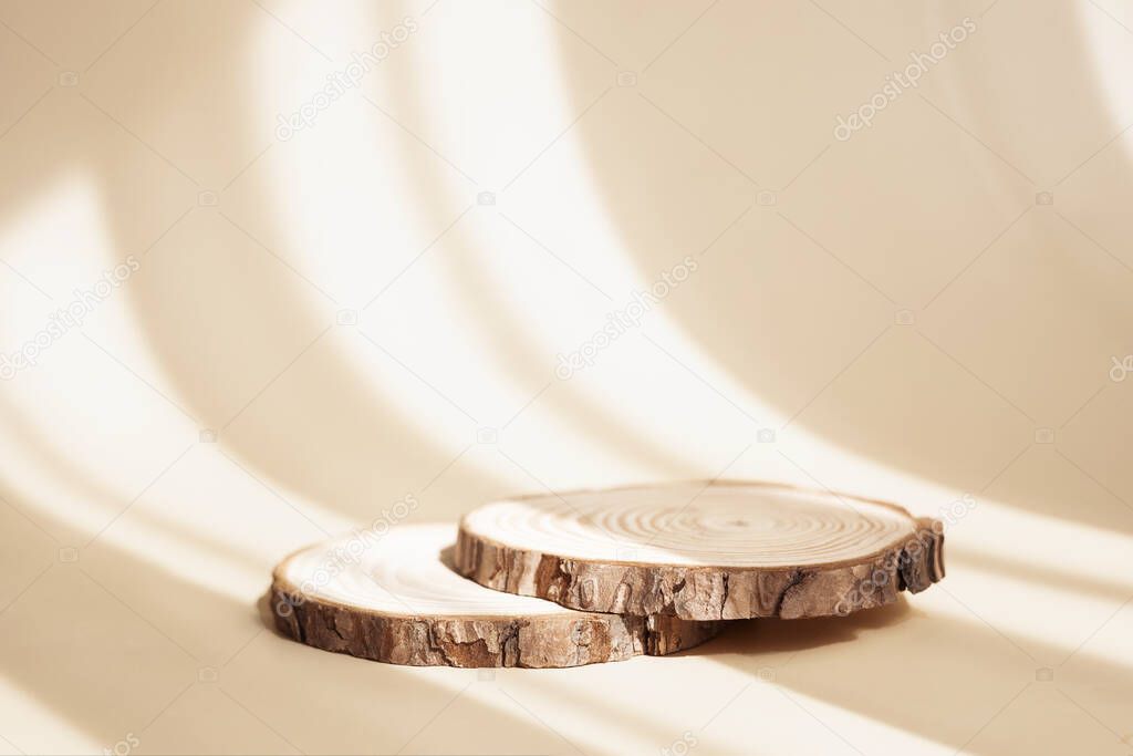 Natural round wooden stand for presentation and exhibitions on pastel beige background with shadow. Mock up 3d empty podium for organic cosmetic product. Copy space.