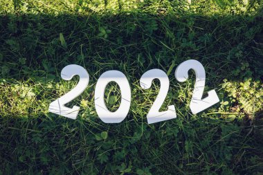 Mutlu yıllar 2022. 2022 numaralı beyaz ahşap yeşil çimlerin üzerinde