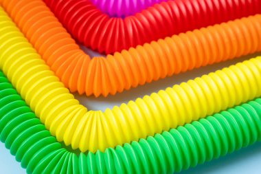 Renkli stres önleyici hareketler mavi arka plandaki çocuklar için pop tüpü duyusal oyuncakları itiyor. Üst manzara, düz yatış. Popüler plastik esnek kıvrımlı boruyla yaratıcı oyunun yakın plan çekimi.