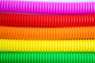 Renkli stres önleyici hareketler mavi arka plandaki çocuklar için pop tüpü duyusal oyuncakları itiyor. Üst manzara, düz yatış. Popüler plastik esnek kıvrımlı boruyla yaratıcı oyunun yakın plan çekimi.