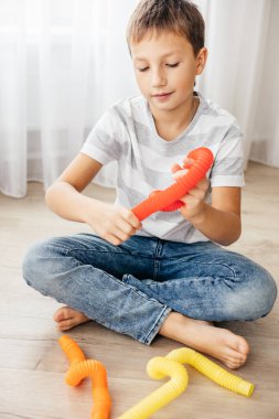 Renkli stres önleyici hareketler çocuklar için pop tüpü oyuncakları itiyor. Çocukların elinde esnek kıvrımlı boru. Duyusal oyuncaklarla oynayan çocuk. Hayal gücünü geliştirmek ve motor becerilerini geliştirmek için eğlenceli oyun..