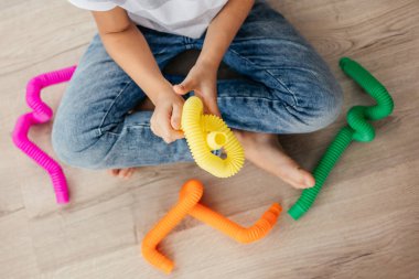 Renkli stres önleyici hareketler çocuklar için pop tüpü oyuncakları itiyor. Çocukların elinde esnek kıvrımlı boru. Duyusal oyuncaklarla oynayan çocuk. Hayal gücünü geliştirmek ve motor becerilerini geliştirmek için eğlenceli oyun..