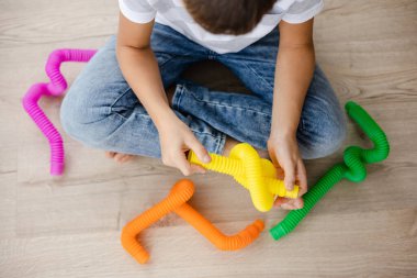 Renkli stres önleyici hareketler çocuklar için pop tüpü oyuncakları itiyor. Çocukların elinde esnek kıvrımlı boru. Duyusal oyuncaklarla oynayan çocuk. Hayal gücünü geliştirmek ve motor becerilerini geliştirmek için eğlenceli oyun..