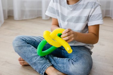 Renkli stres önleyici hareketler çocuklar için pop tüpü oyuncakları itiyor. Çocukların elinde esnek kıvrımlı boru. Duyusal oyuncaklarla oynayan çocuk. Hayal gücünü geliştirmek ve motor becerilerini geliştirmek için eğlenceli oyun..