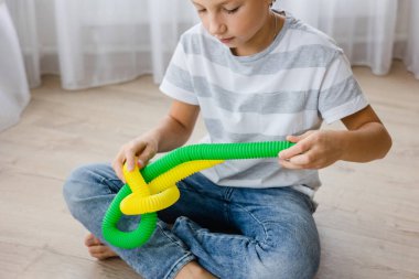 Renkli stres önleyici hareketler çocuklar için pop tüpü oyuncakları itiyor. Çocukların elinde esnek kıvrımlı boru. Duyusal oyuncaklarla oynayan çocuk. Hayal gücünü geliştirmek ve motor becerilerini geliştirmek için eğlenceli oyun..