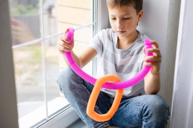 Renkli stres önleyici hareketler çocuklar için pop tüpü oyuncakları itiyor. Çocukların elinde esnek kıvrımlı boru. Duyusal oyuncaklarla oynayan çocuk. Hayal gücünü geliştirmek ve motor becerilerini geliştirmek için eğlenceli oyun..