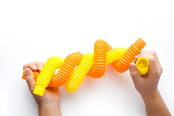 Çocuklar için renkli stres önleyici pop tüpü duyusal oyuncakları. Çocukların elindeki esnek kıvrımlı boru beyaz arka planda izole edilmiş. Hayal gücünü geliştirmek ve motor becerilerini geliştirmek için oynuyorlar. Üst görünüm