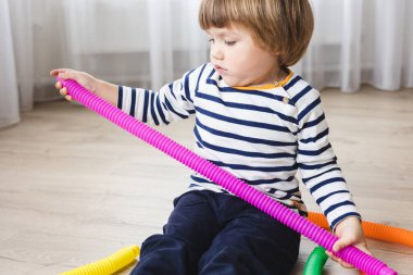 Renkli stres önleyici hareketler çocuklar için pop tüpü oyuncakları itiyor. Çocukların elinde esnek kıvrımlı boru. Duyusal oyuncaklarla oynayan çocuk. Hayal gücünü geliştirmek ve motor becerilerini geliştirmek için eğlenceli oyun..