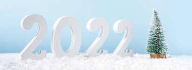 Mutlu yıllar 2022. Süslü beyaz numara 2022, köknar ağacı ve kar mavi arka planda izole edilmiş. Fotokopi alanı olan bir Noel kartı. Pankart