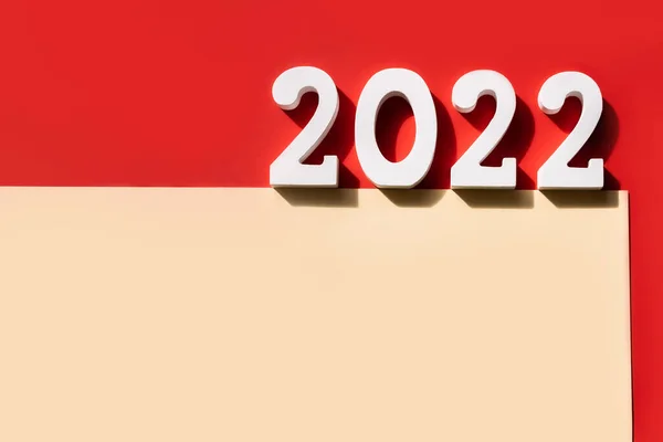 2022年新年 白色2022号和空白米色纸 带有红色背景的复制空间 圣诞贺卡 干净的纸 邀请函模板 顶视图 复制空间 — 图库照片