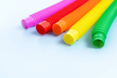 Renkli stres önleyici hareketler mavi arka plandaki çocuklar için pop tüpü duyusal oyuncakları itiyor. Üst manzara, düz yatış. Popüler plastik esnek kıvrımlı boruyla yaratıcı oyunun yakın plan çekimi.